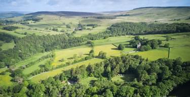 Header image Aerial view of North Lees campsite in summer North Lees Hall in background 1